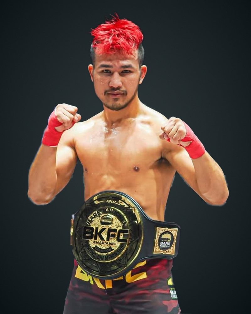 Frankke Kritsana Srisang with red hair and red hand wraps, in a fighting guard wearing the BKFC Thailand championship belt